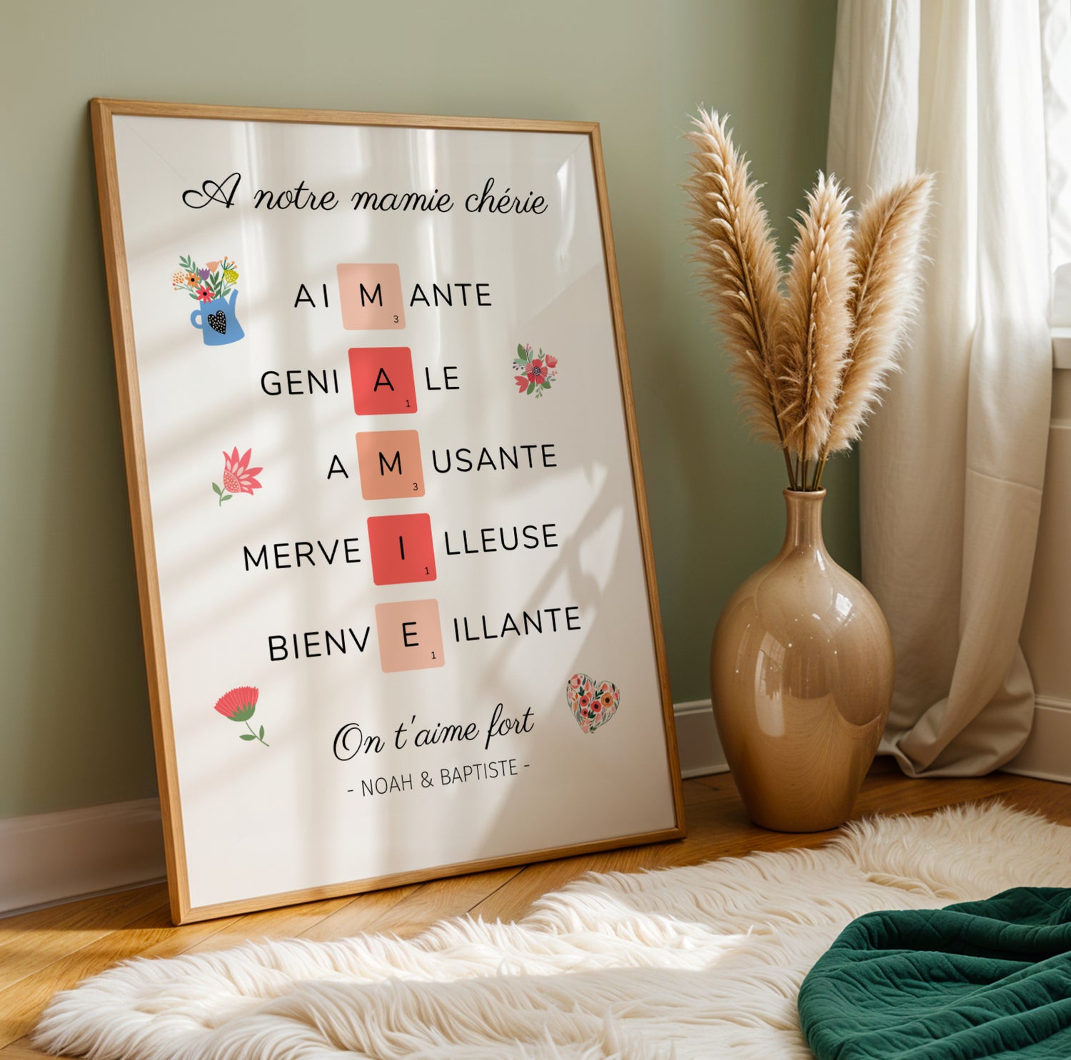 Affiche Mamie Personnalisée with loving adjectives and red letters spelling MAMIE, framed on floor next to vase and pampas.
