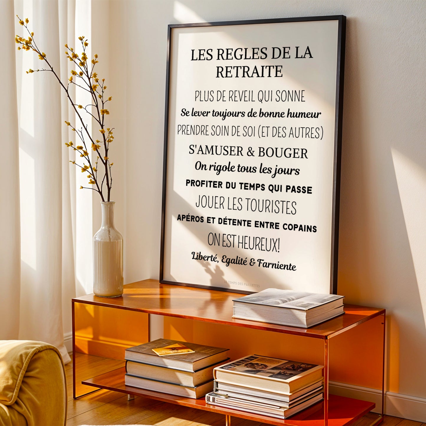 A personalized "Affiche cadeau départ à la retraite" par Le Temps des Paillettes is framed and leans on an orange shelf with books and yellow flowers, sunlight creating a warm déco ambiance perfect for celebrating retirement.