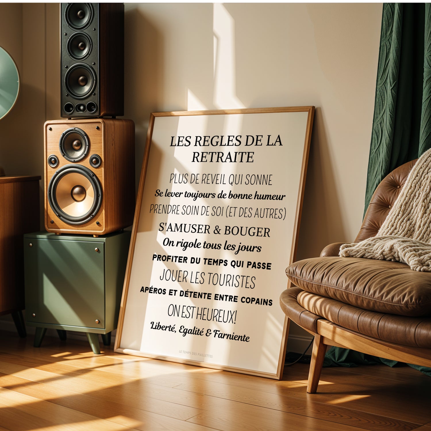 L’Affiche cadeau départ à la retraite - poster retraiter personnalisé par Le Temps des Paillettes est posée contre un mur dans une pièce chaleureuse avec fauteuil en cuir, parquet, plante et lumière douce, idéale comme décoration retraite.