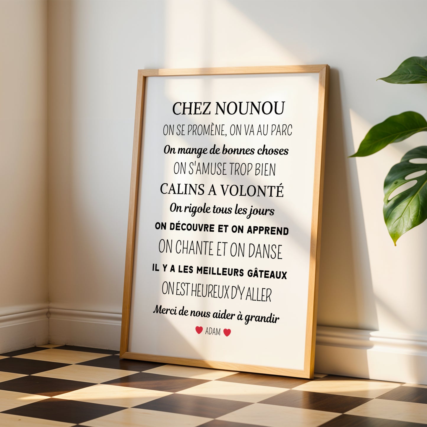 A personalized "Affiche chez nounou" poster by Le Temps des Paillettes rests on the floor, bathed in sunlight and surrounded by plants—an ideal cadeau personnalisé nounou to express gratitude for a caring nanny.