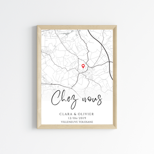 Affiche encadrée avec une carte en noir et blanc marquée d'une épingle rouge. Le texte 'Chez nous' est écrit en calligraphie, suivi des noms 'Clara & Olivier', de la date '12/06/2019' et du lieu 'Villeneuve