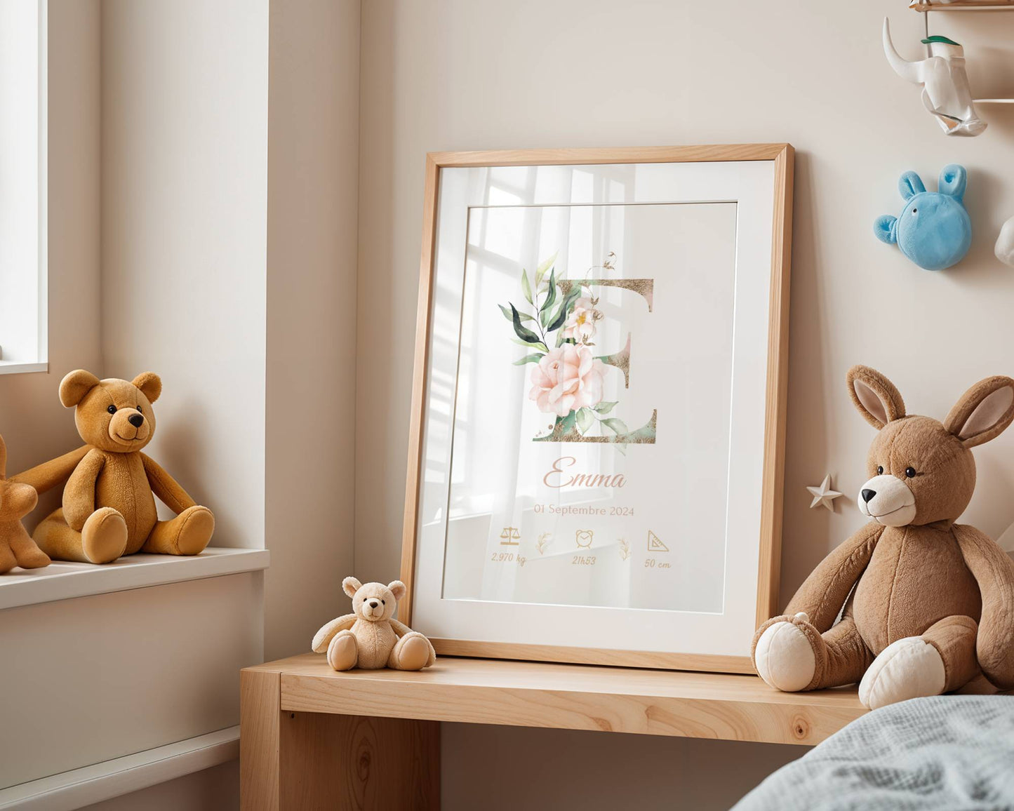 Affiche de naissance personnalisée prénom et initiale fleurs rose pastel, nom Emma et ses détails de naissance, exposée sur une étagère en bois dans une chambre d'enfant avec peluches et lumière douce naturelle.