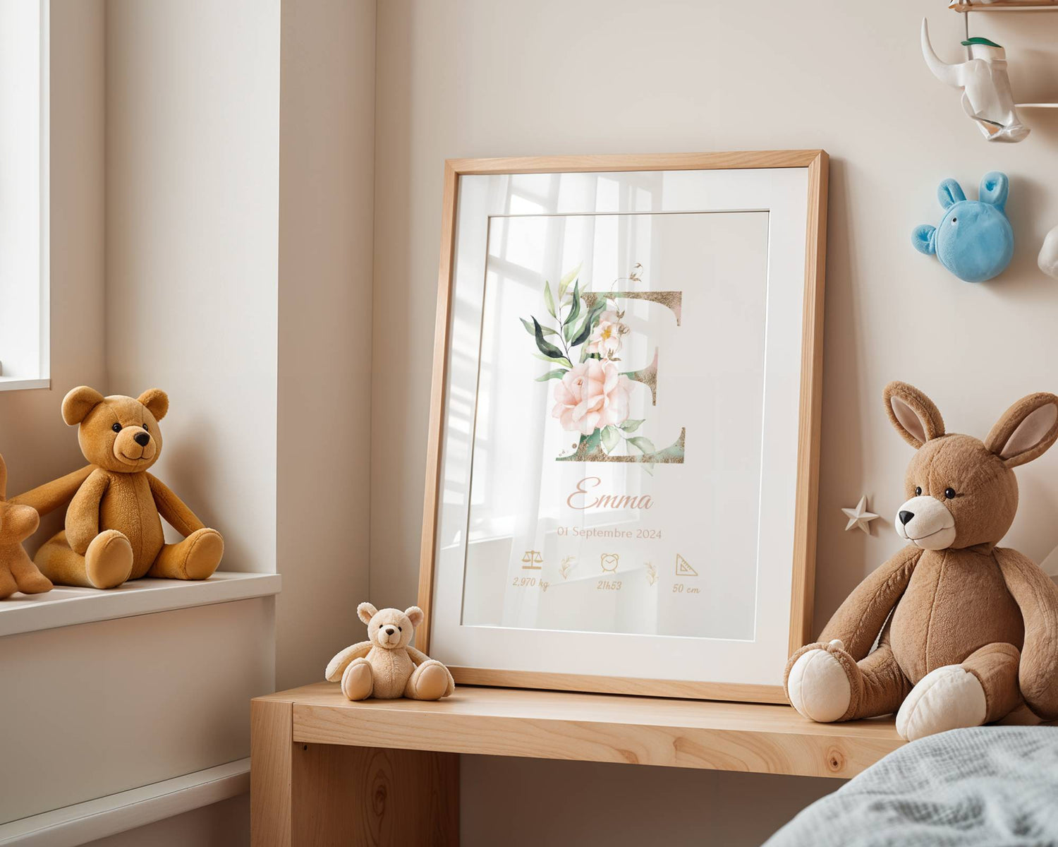 Affiche de naissance personnalisée prénom et initiale fleurs rose pastel, nom Emma et ses détails de naissance, exposée sur une étagère en bois dans une chambre d'enfant avec peluches et lumière douce naturelle.
