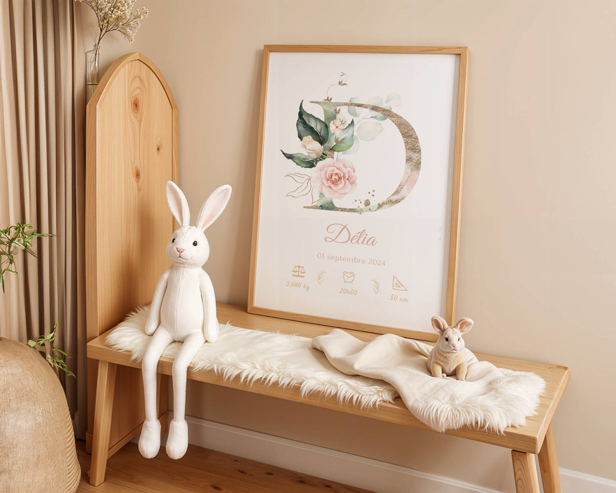 A cozy nursery features a wooden bench, white plush bunny toys, a soft fur throw, and the "Affiche de naissance personnalisée prénom et initiale fleurs rose pastel"—a perfect décor piece and charming cadeau naissance for a little girl's room.