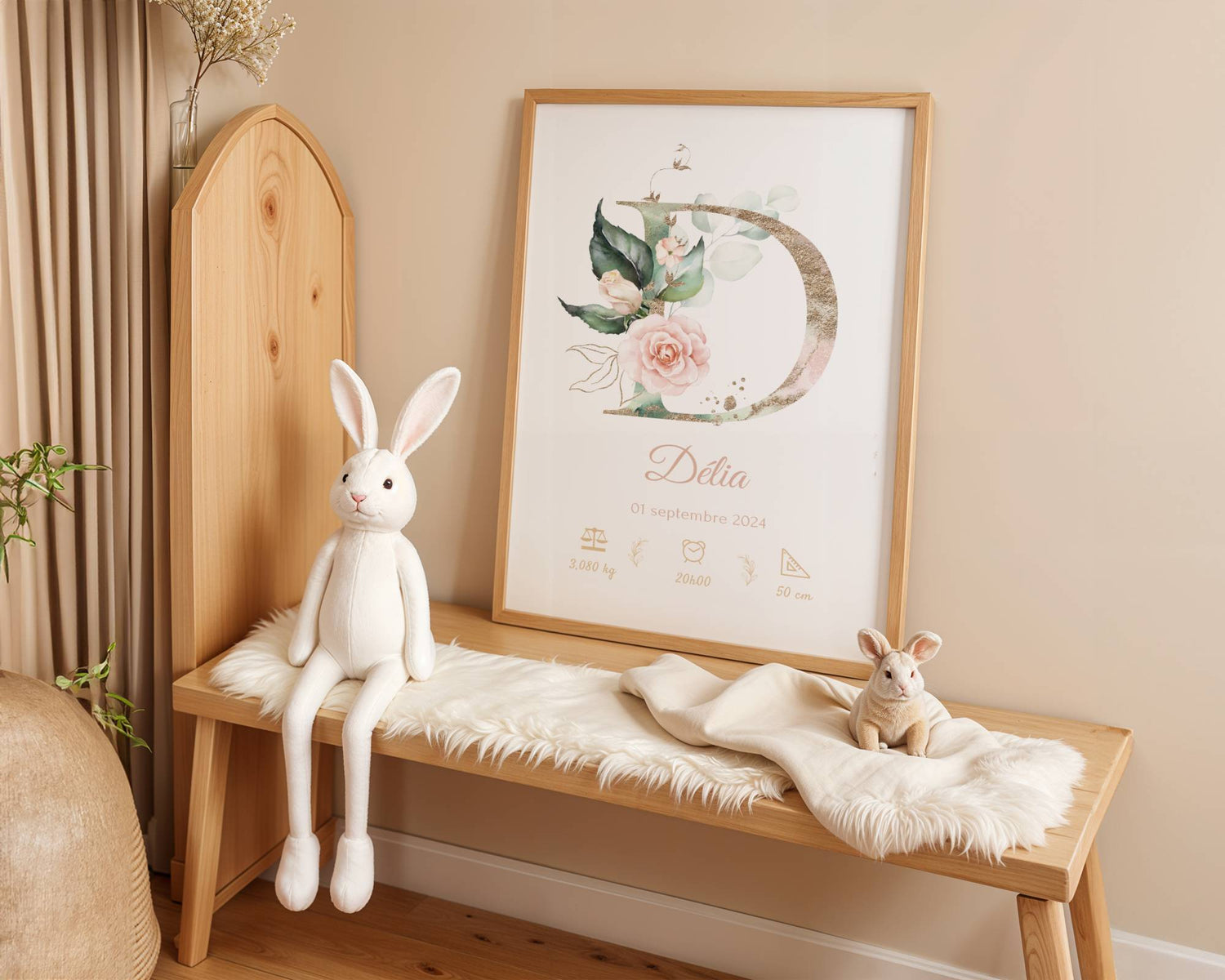 A cozy nursery features a wooden bench, white plush bunny toys, a soft fur throw, and the "Affiche de naissance personnalisée prénom et initiale fleurs rose pastel"—a perfect décor piece and charming cadeau naissance for a little girl's room.