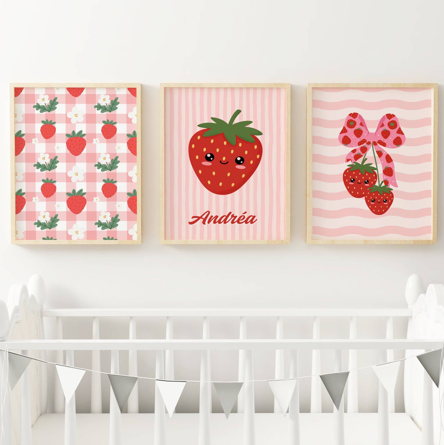 Trio d'affiches murales enfantines au thème fraise kawaii et esthétique coquette. La première affiche présente un motif vichy rose et blanc parsemé de fraises et fleurs blanches. La seconde, centrale, montre une grande fraise souriante personnalisée avec le prénom Andréa sur fond rayé rose. La troisième affiche illustre deux fraises kawaii suspendues à un ruban rose à motifs fraises sur un fond de vagues roses. Palette de couleurs rouge, rose pastel et vert.